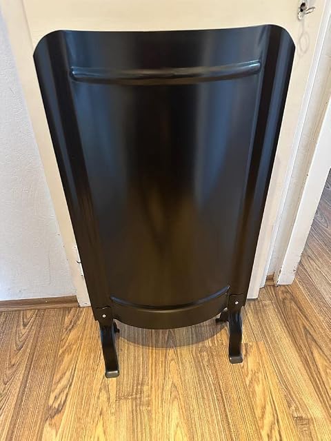 Una pantalla de estufa lisa y negra de pie sobre sus patas, de 91 por 46 centímetros